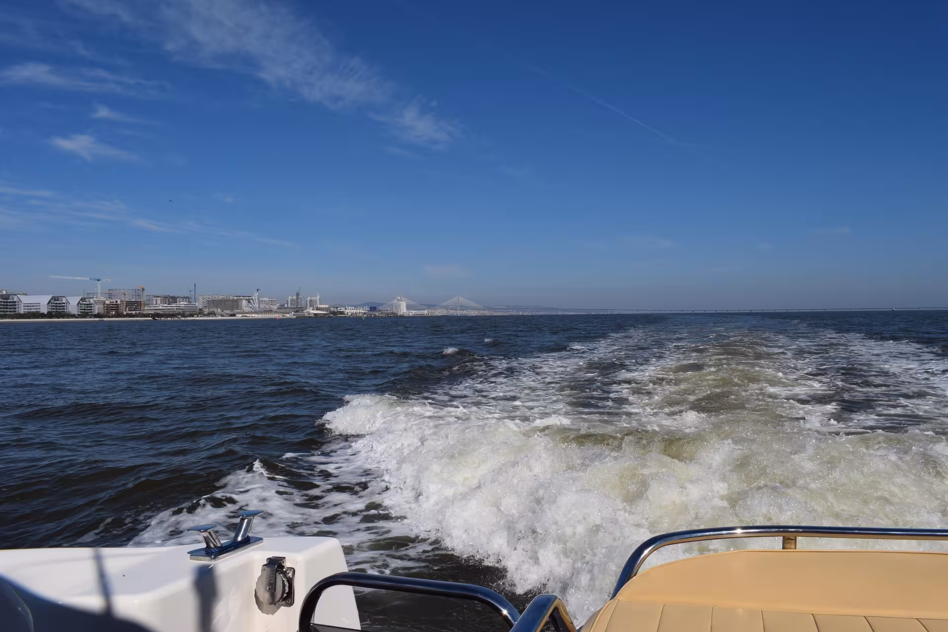 Speedboat wake on the Tagus River with Lisbon waterfront and Vasco da Gama Bridge in the distance, Lisbon tour