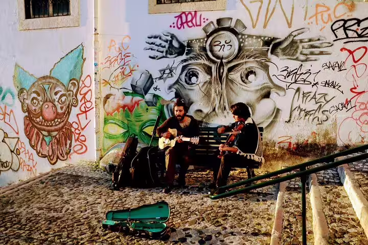Street musicians perform against vibrant graffiti in Lisbon, showcasing the city's rich culture and lively atmosphere on a food tour.