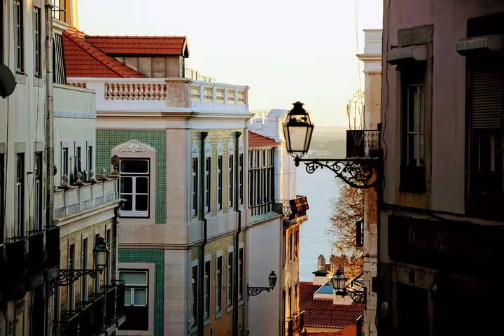 Charming Lisbon street view at sunset, showcasing traditional architecture and atmospheric lanterns, perfect for culture and food tours.