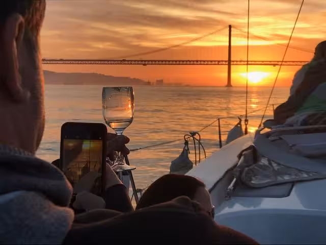 Wine glass toast on Lisbon sunset boat tour with 25 de Abril Bridge views on the Tagus River cruise