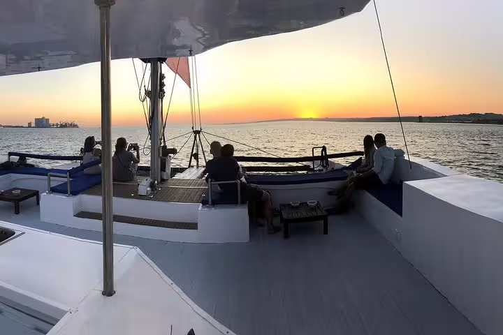 Passengers enjoy a stunning sunset view aboard a catamaran on the Tagus River during a Lisbon sunset cruise.