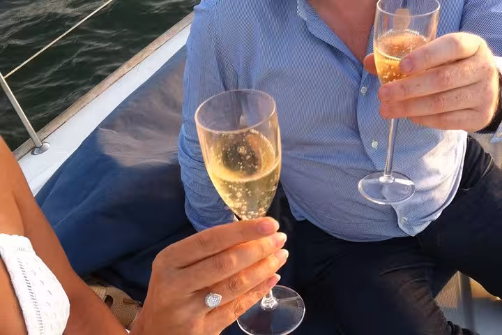 Couple toasting with sparkling wine on a private Lisbon sunset cruise, romantic 2-hour boat experience