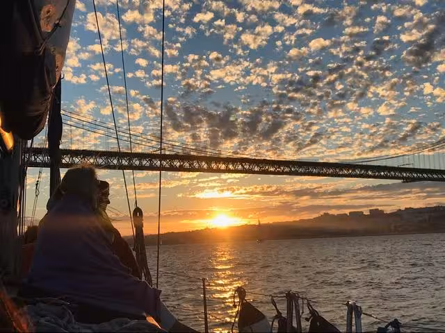 Lisbon sunset cruise under 25 de Abril Bridge on the Tagus River, sailing boat tour with wine