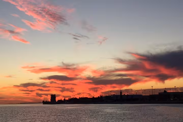 Fiery sunset over Lisbon waterfront on a small-group sailing cruise on the Tagus River with a drink included