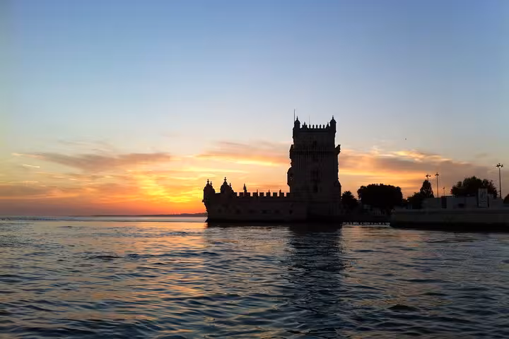 Belém Tower silhouetted at sunset from the Tagus River on a Lisbon luxury sailing yacht tour with 2 drinks