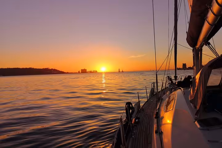 Luxury sailing yacht at sunset on the Tagus River in Lisbon, golden horizon during cruise with 2 drinks