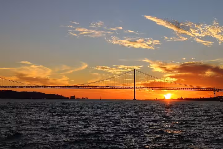 Lisbon sunset sailing tour view of 25 de Abril Bridge over the Tagus River from a luxury yacht cruise
