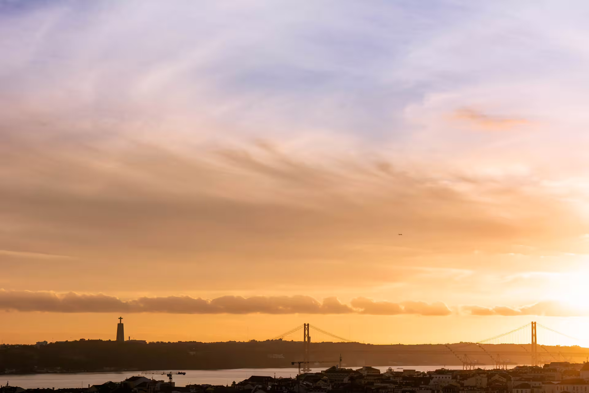 Sunset view of Lisbon's skyline with the iconic bridge, perfect for a private Christmas lights photo walk tour.