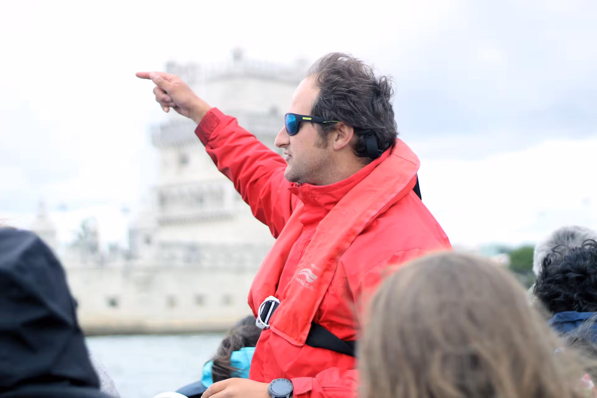 Skipper in red jacket briefing guests on Lisbon sunset speedboat tour near Belém Tower on the Tagus