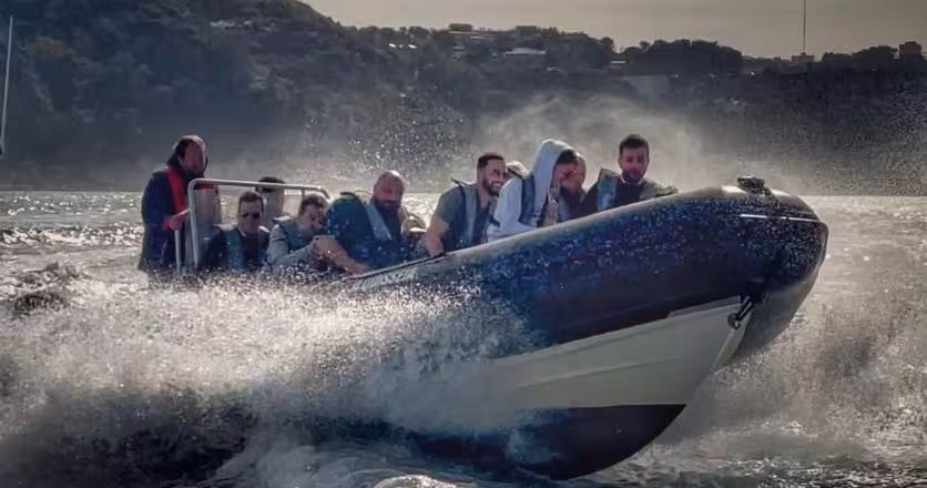 Lisbon sunset speedboat tour with passengers on a RIB speeding across the Tagus River, spray and city views