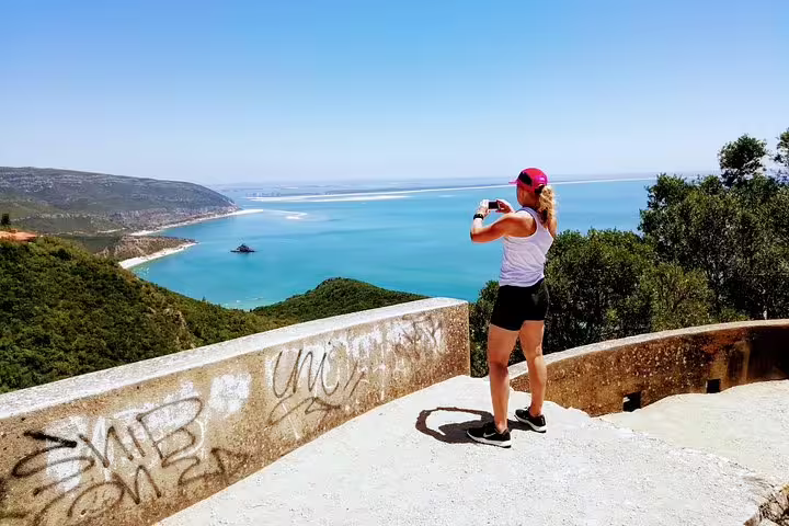 Woman capturing breathtaking coastal views in Lisbon; perfect surf and wine tour experience amidst stunning landscapes.