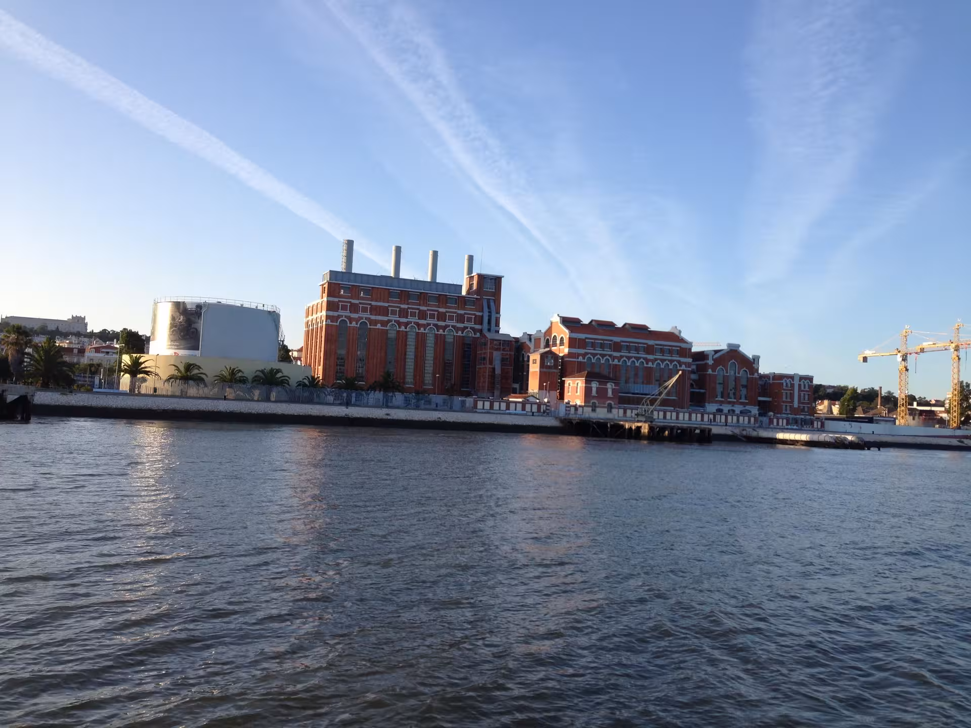View of Lisbon’s riverside industrial buildings from a private Tagus River sightseeing cruise at sunset