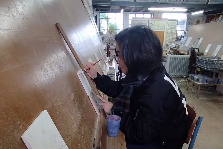 A participant paints tiles at a private workshop, part of a unique tour including wine tasting and exploring Sesimbra.
