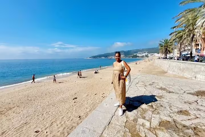 A woman enjoys the sunny beach promenade in Sesimbra, Portugal, highlighting the scenic coastal backdrop of the tour.