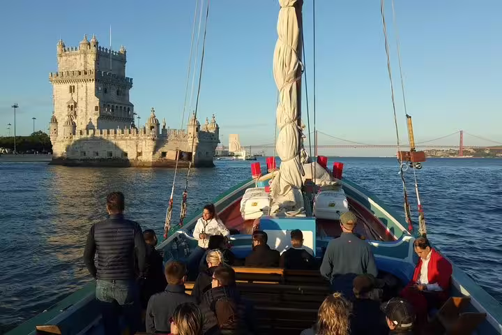 Passengers on a traditional boat enjoy views of Belem Tower during a guided sightseeing cruise in Lisbon.