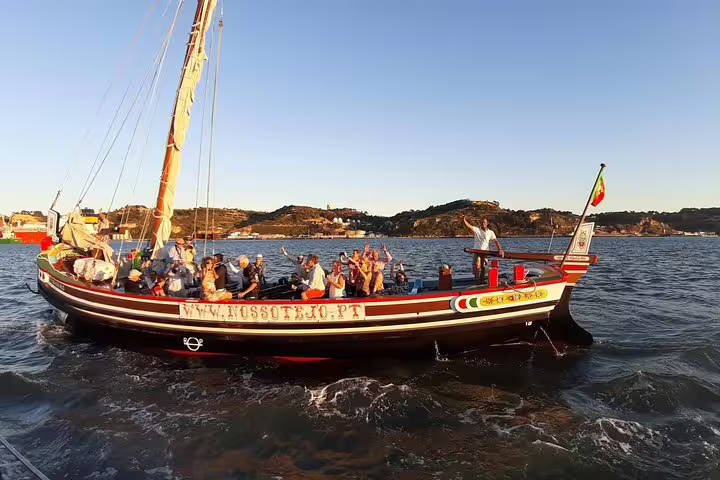 A traditional Lisbon boat sails with passengers, showcasing the city's picturesque waterfront.