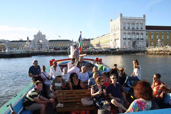 Tourists relax on a Lisbon sightseeing boat with views of historic city landmarks.