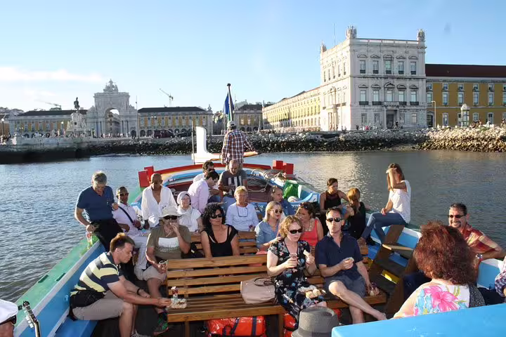 Group of tourists enjoying a Lisbon boat cruise, surrounded by historic architecture and vibrant cityscape.