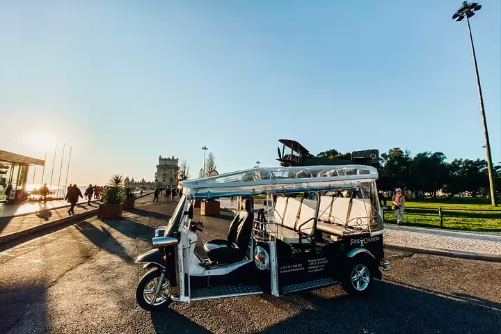 Scenic view of a tuk-tuk near Belém Tower, capturing the essence of a Lisbon private tour at sunset.