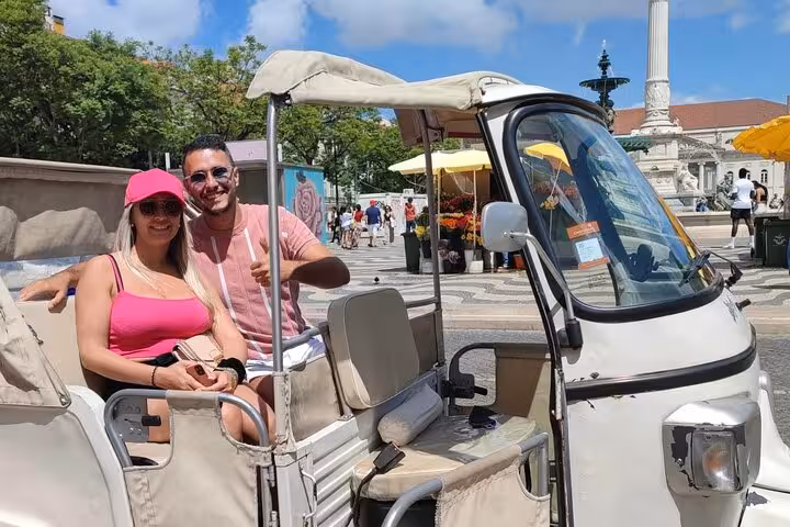 Couple posing in a tuk tuk at Lisbon Old Town square on a 1-hour sightseeing tuk tuk tour experience