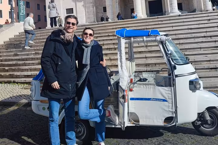 Couple posing by a Lisbon tuk-tuk on a 2-hour city tour, exploring historic landmarks and viewpoints