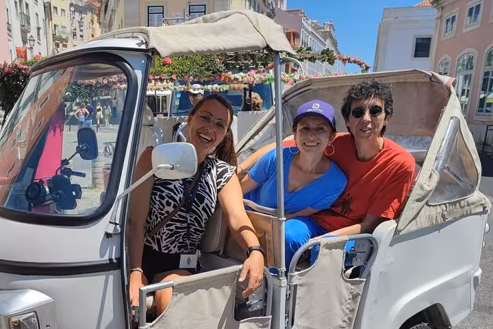 Smiling guests in tuk-tuk on Lisbon 2-hour city tour, exploring historic streets and viewpoints with local guide