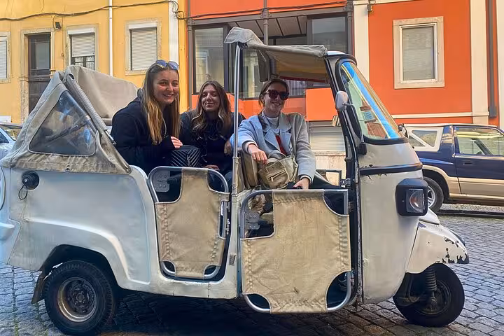 Private Lisbon tuk tuk tour with smiling guests near Praça do Comércio, 1-hour Old Town sightseeing