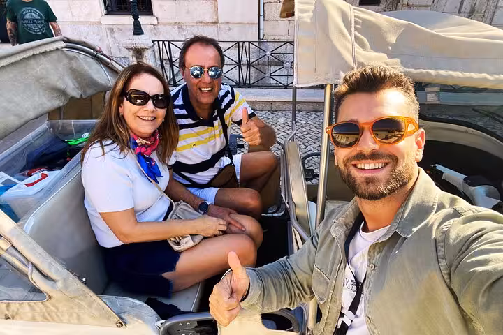 Smiling travelers with driver in open-air tuk tuk on Lisbon Old Town 1-hour tour, exploring historic streets