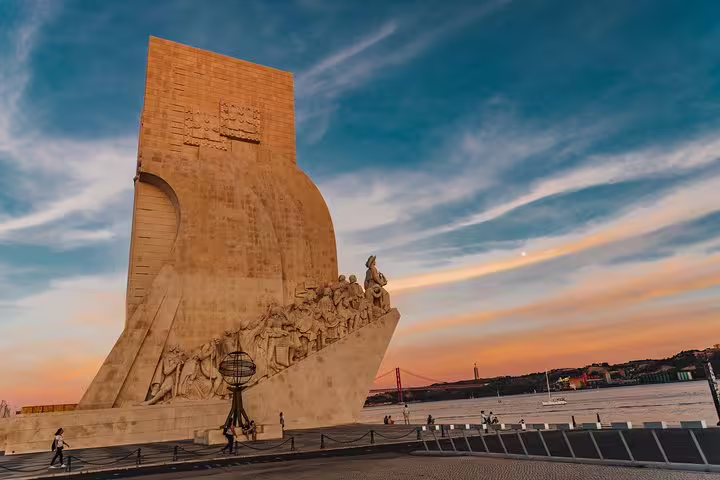 Scenic view of Lisbon's famous monument at sunset, highlighting the vibrant sky and waterfront on a tuk tuk tour.