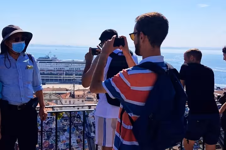 Tour guests taking photos at a Lisbon viewpoint over the Tagus River during a 1-hour tuk tuk tour