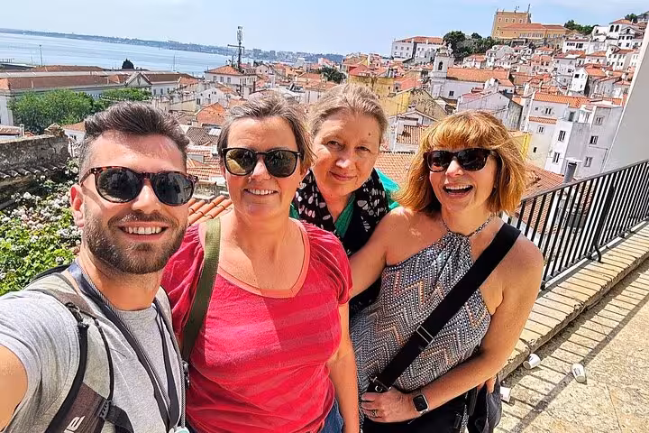 Group selfie at Lisbon viewpoint on a 3-hour private tuk tuk tour, with Alfama rooftops and Tagus River