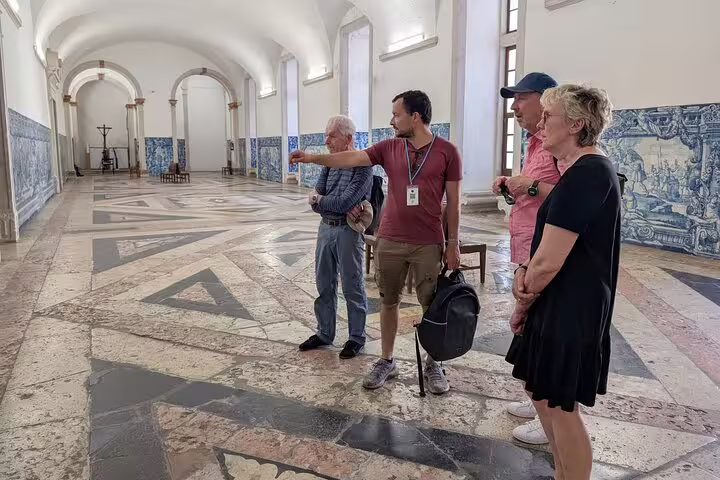 Tour guide leading a group through a historic Lisbon building on a private TukTuk tour, highlighting local culture and architecture.
