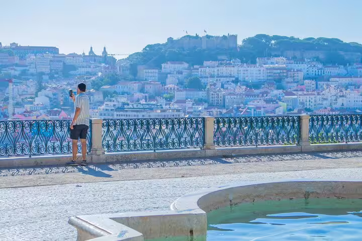 Scenic view of Lisbon cityscape from a viewpoint with a man taking photos, ideal for a private TukTuk tour with local guide.