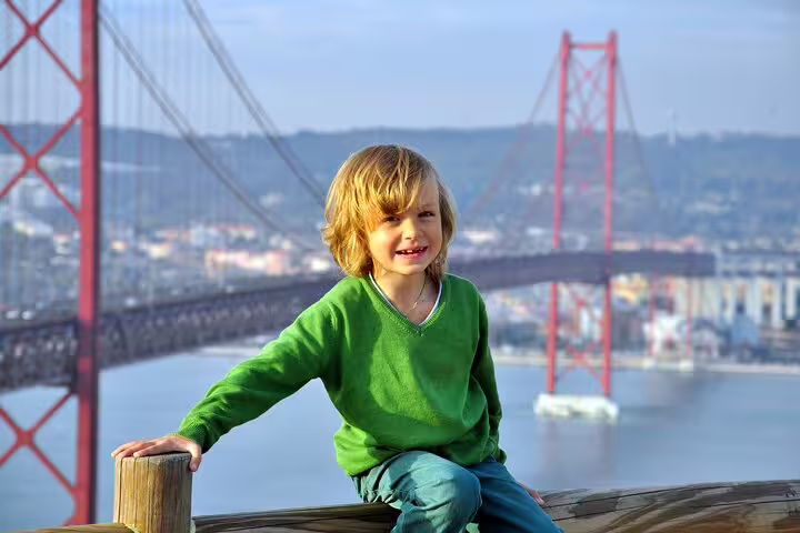 Child enjoying a scenic view of Lisbon's iconic 25 de Abril Bridge during a private walking tour, highlighting city secrets.