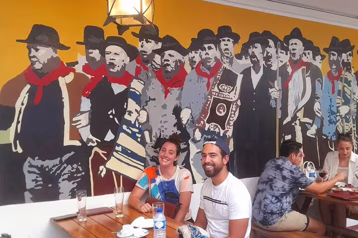 Tourists enjoy a Lisbon café with vibrant mural during a small group walking tour.