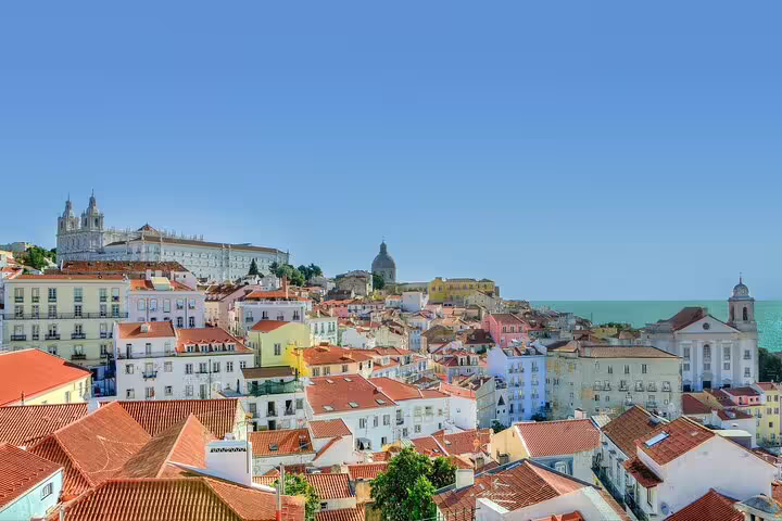 Scenic view of Lisbon's colorful rooftops and historic architecture with clear blue sky, ideal for walking tours.