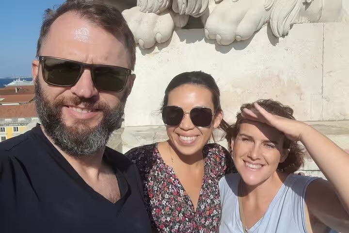 Three happy tourists enjoying Lisbon's sunny weather on a walking tour, capturing memorable moments.