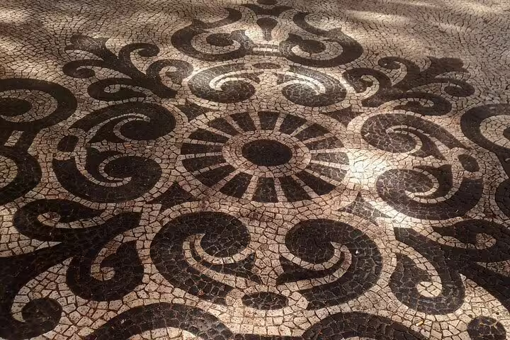 Intricate black and white mosaic pavement pattern in Lisbon, showcasing Portuguese artistry on walking tours.