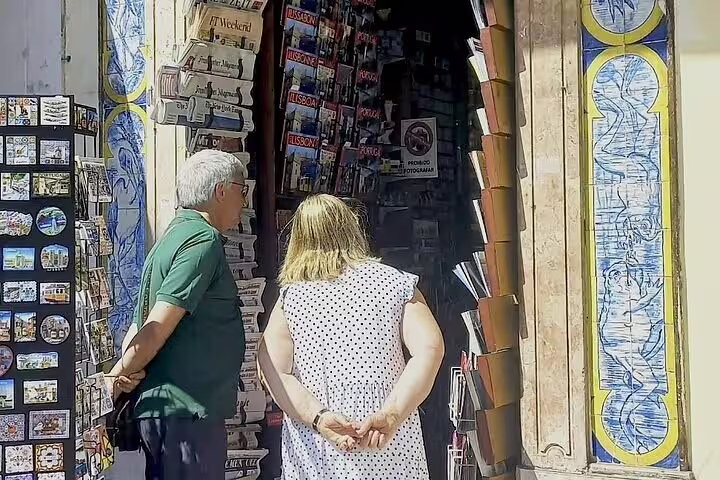 Tourists browse postcards at a vibrant souvenir shop during a small group walking tour in Lisbon.