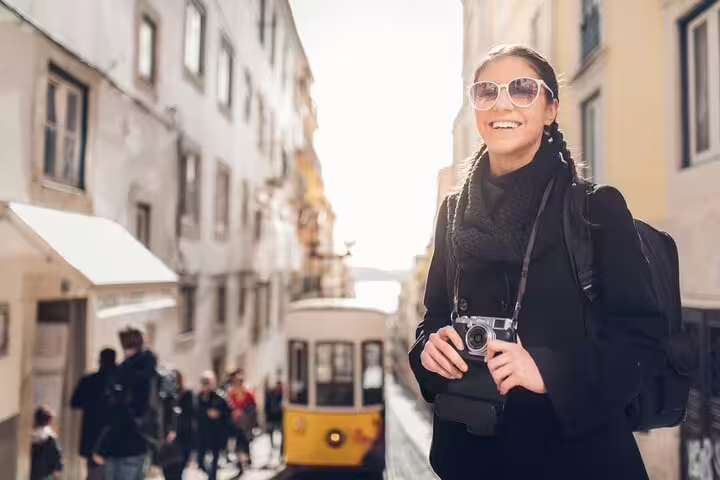Smiling tourist with camera explores Lisbon’s charming streets and historic tram on a private walking tour.