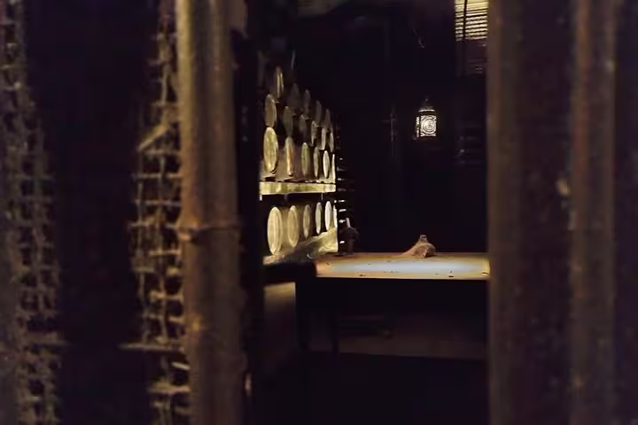 Dimly lit wine cellar with stacked barrels, perfect for a private tiles painting workshop and wine tasting in Sesimbra.