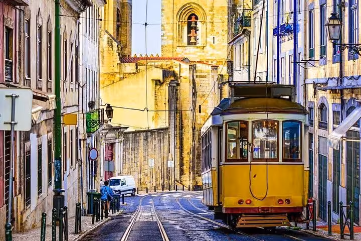 Historic yellow tram navigating a charming street in Lisbon's Alfama district, ideal for private city tours.