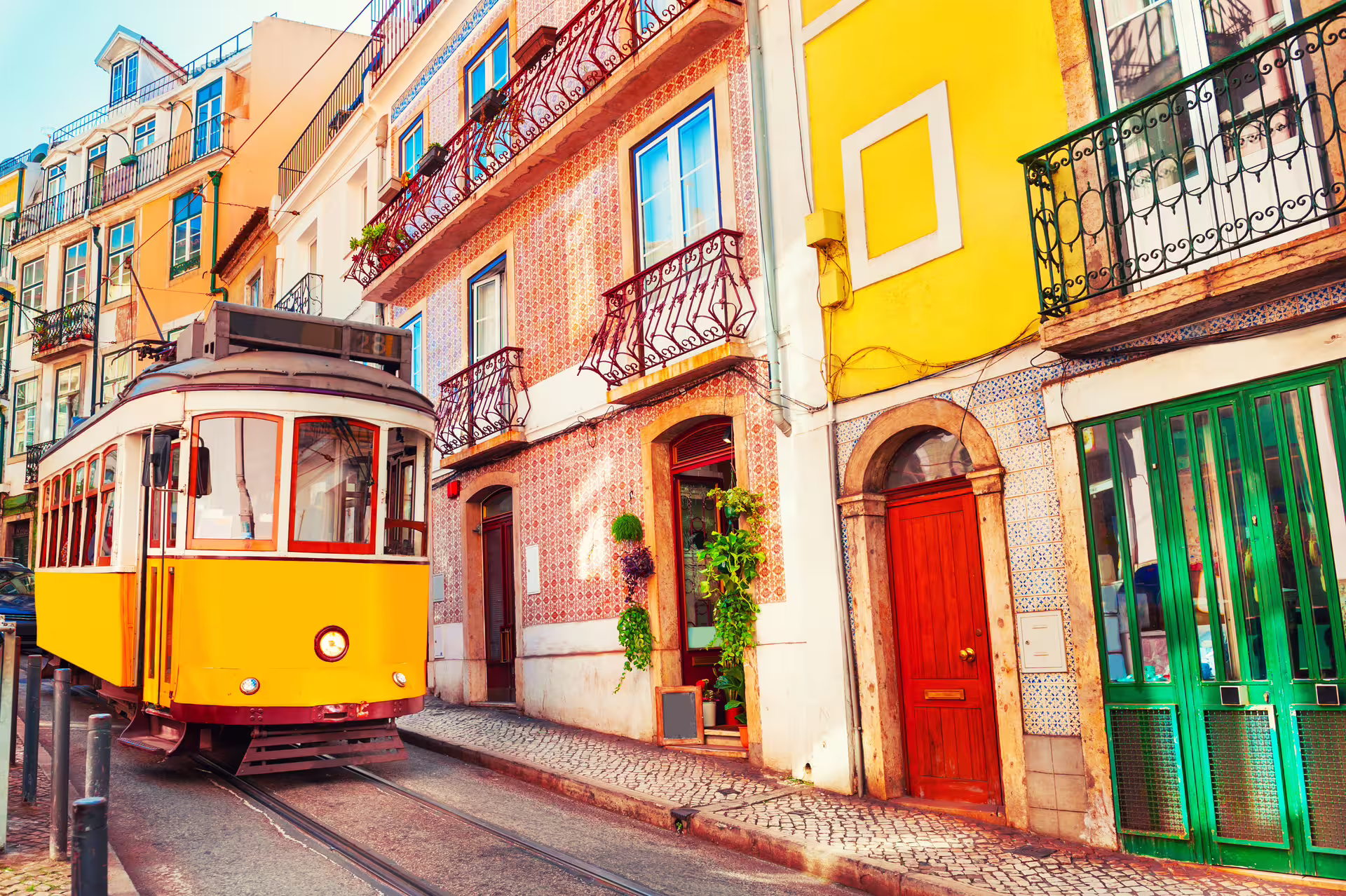 Iconic yellow tram passing colorful historic buildings in Lisbon, capturing the charm of a private half-day tour experience.