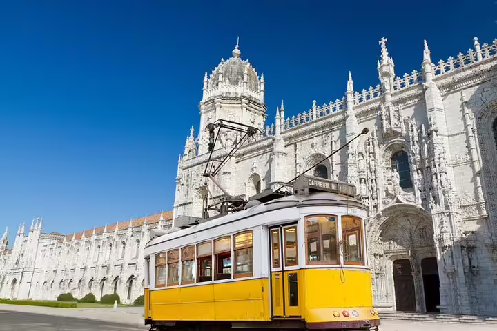 Historic yellow Lisbon tram passing the iconic Jerónimos Monastery, perfect for a custom full-day private tour experience.