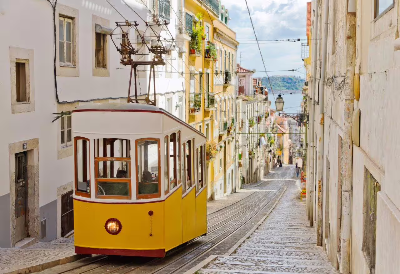 Historic yellow tram on a scenic, narrow street in Lisbon, Portugal, perfect for a self-drive discovery tour.