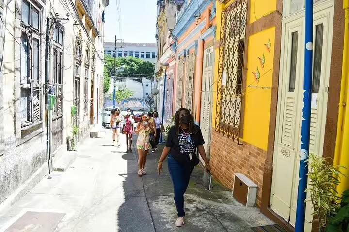 Tour group strolls through colorful alleys of Rio's Little Africa, experiencing rich Afro-Brazilian cultural heritage.