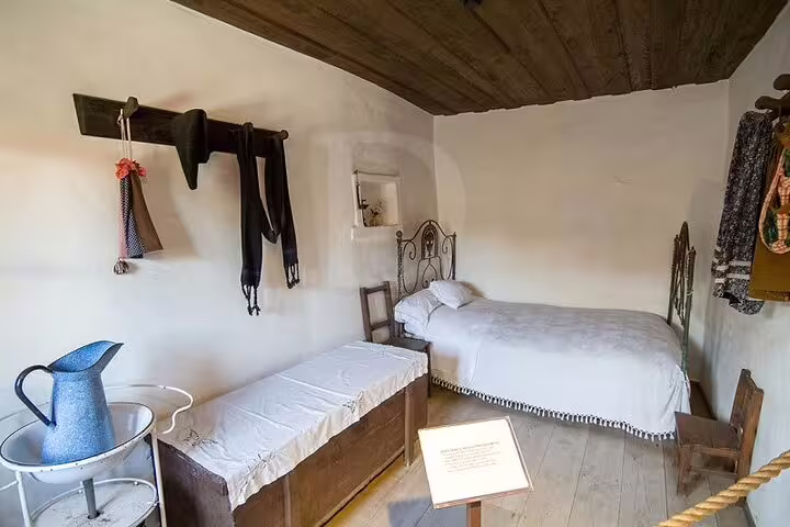 Interior of a preserved bedroom in the Little Shepherds' house, featuring vintage furnishings and rustic decor.