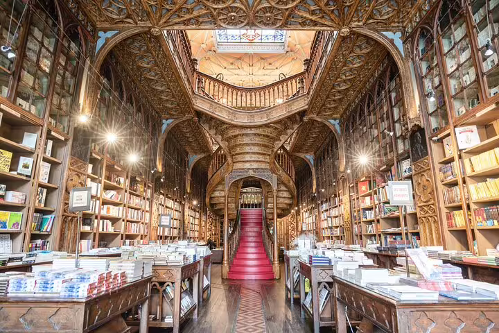 Intricate interior of Livraria Lello in Porto, showcasing ornate wooden staircase and bookshelves, featured in tuk-tuk tour.
