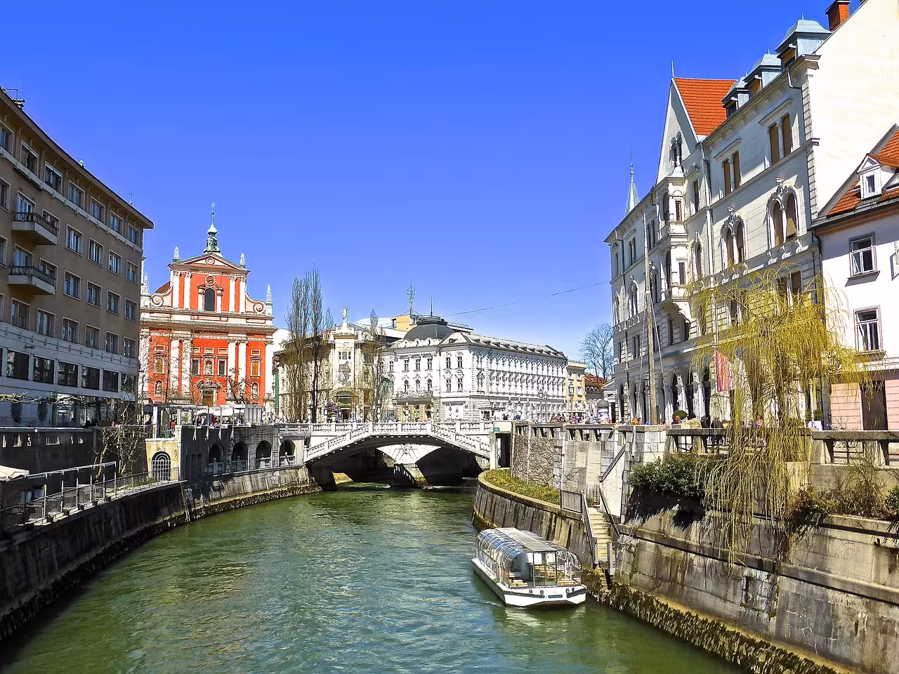Ljubljana Old Town riverfront with cruise boat on Ljubljanica, key stop on Ljubljana & Lake Bled tour