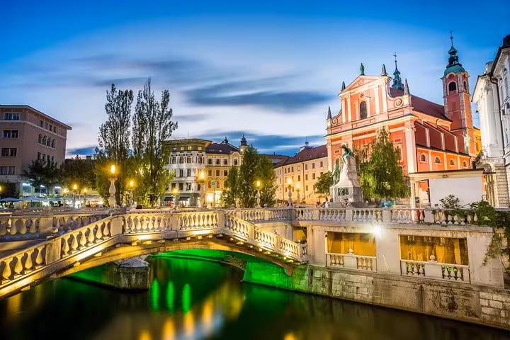Evening view of Ljubljana’s Triple Bridge and Franciscan Church, a highlight on the Slovenia day tour
